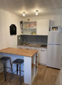 uma cozinha com um frigorífico branco, uma mesa e bancos em Joli appartement proche océan et centre ville em Lacanau