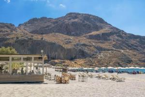 a beach with chairs and tables and a mountain at Villa Mayeia in Plakias