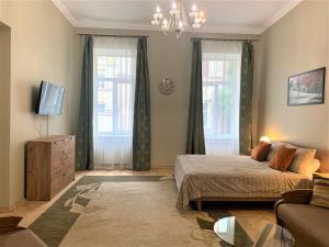 a bedroom with a bed and a couch and windows at Glorious Apartment Near The Old City in Lviv