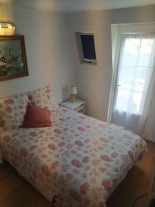 een slaapkamer met een bed met een bloemendeken en een raam bij Les pavés bleus - Cœur de Deauville in Deauville