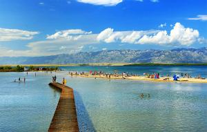 a group of people on a beach with a pier at Apartman Enjoy Nin in Nin