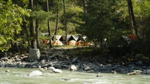 un groupe de moutons nageant dans une rivière avec des tentes dans l'établissement Himtrek Riverside Camps, Kasol, à Kasol