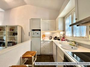 a white kitchen with a sink and a refrigerator at #Villa Niovi by halu! Sani Villas in Sani Beach