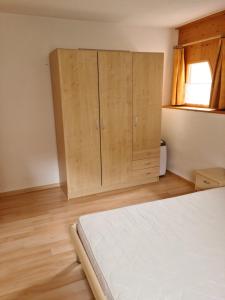 1 dormitorio con 1 cama y armarios de madera en Lumpaz, en Santa María Val Mustair