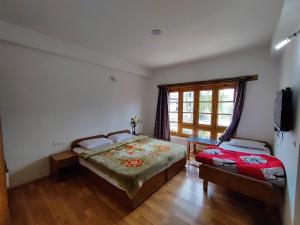 a bedroom with two beds and a window at Jig Gyas Guest House in Leh