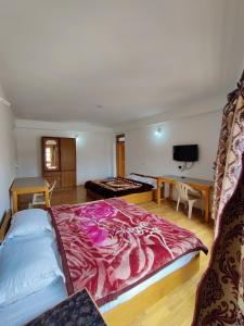 um quarto com uma cama grande e um cobertor vermelho em Jig Gyas Guest House em Leh
