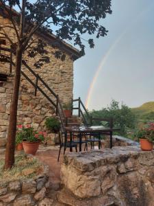 um pátio com uma mesa e cadeiras e um arco-íris em Refugio La Cabrera em Mont-ral