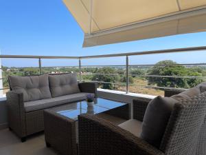 a balcony with wicker chairs and a glass table at Luxury Rhodian Panorama in Ixia