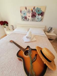 una guitarra sentada en una cama con un sombrero en Rooms Villa Gala, en Mlini