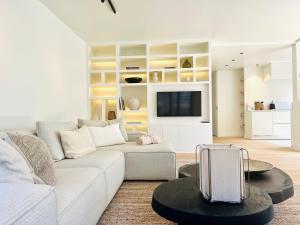 a living room with a white couch and a tv at luxe appartement op topligging in Knokke-Heist