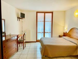 1 dormitorio con 1 cama, vestidor y escritorio en Hotel Edelweiss, en San Zeno di Montagna