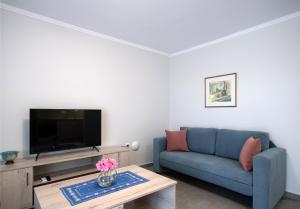 ein Wohnzimmer mit einem blauen Sofa und einem TV in der Unterkunft Fragiato Apartment in Lefkada Town