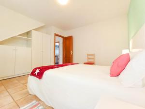 1 dormitorio con 1 cama blanca grande con almohadas rojas en A casa da panadeira, en Cambados