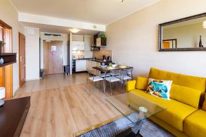 a living room with a yellow couch and a kitchen at VacationClub – Olympic Park Apartament B302 in Kołobrzeg