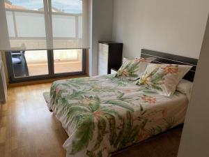 1 dormitorio con 1 cama con edredón de flores y ventana en Apartamento Cabodeiro - Illa de Arousa, en A Illa de Arousa