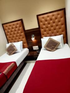 two beds in a hotel room with a red blanket at Hotel New Silver Elite in Mumbai