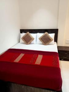 una camera con un letto rosso e bianco con due cuscini di Hotel New Silver Elite a Mumbai