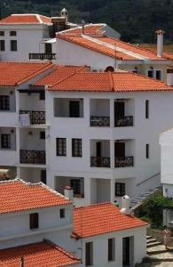 a large white building with orange roofs at Achinos Apartments and Maisonettes in Kokkari