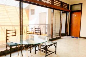 a glass table and chairs in a room with a balcony at KoolKost near Universitas Wijaya Kusuma (Minimum Stay 30 Nights) in Dukuhkupang