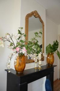 a mirror and two vases on a table with flowers at Huize Maurits in The Hague