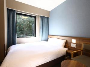 a bedroom with a white bed and a window at Dormy Inn Express Fujisan Gotemba in Gotemba
