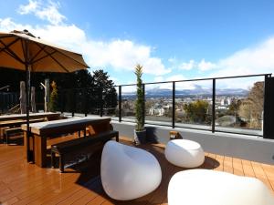 a balcony with a table and chairs and an umbrella at Dormy Inn Express Fujisan Gotemba in Gotemba