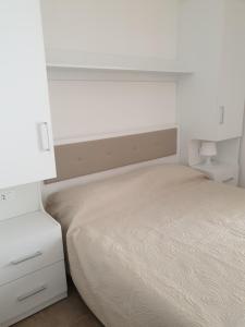een witte slaapkamer met een bed en een nachtkastje bij Green Park Residence in Foce Varano