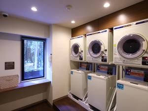 a laundry room with three washing machines and a window at Dormy Inn Express Fujisan Gotemba in Gotemba