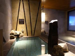 a swimming pool in a room with rocks at Dormy Inn Express Fujisan Gotemba in Gotemba