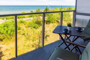 balcone con tavolo e vista sull'oceano di VacationClub – Jantaris Apartament A24 a Mielno