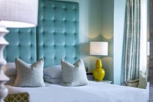 a bedroom with a bed with a blue headboard and pillows at Roslin Beach Hotel in Southend-on-Sea