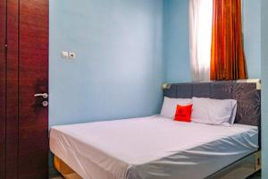 a small bed in a blue room with a red pillow at KoolKost Syariah @ Dukuh Kupang (Minimum Stay 30 Nights) in Putat-wetan