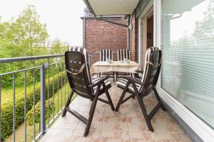 d'une terrasse avec une table et des chaises sur un balcon. dans l'établissement Nordseegartenpark Friesenstolz, à Bensersiel