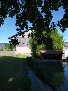 a barn next to a river with a building at Ferme du Vaucanu in Vimoutiers