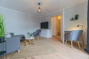 ein Wohnzimmer mit einem Sofa, Stühlen und einem Tisch in der Unterkunft Spreewald-Apartment, 75qm, 2 Schlafzimmer, Tiefgarage, Balkon, Netflix, Waschtrockner in Cottbus