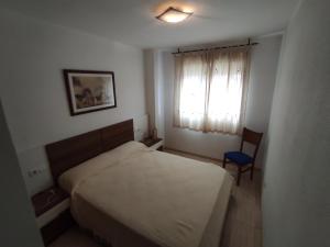 sypialnia z łóżkiem, krzesłem i oknem w obiekcie Apartamento LAIA w mieście Oropesa del Mar