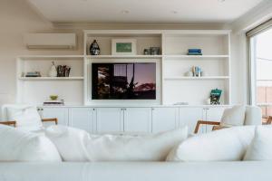 a living room with white furniture and a flat screen tv at Stunning Harbourside Home with Panoramic Views in Sydney