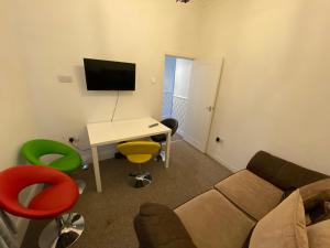 a living room with a couch and a desk and a tv at The Bay En-suite Room in Plymouth