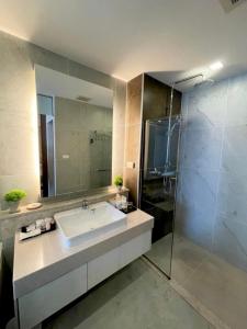 La salle de bains est pourvue d'un lavabo et d'une douche en verre. dans l'établissement The Astra Suites Condo, à Chiang Mai