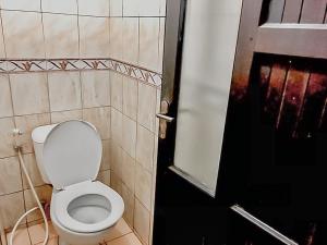 a bathroom with a white toilet and a black door at Hotel Aida Syariah Mitra RedDoorz in Samarinda