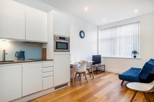 una cocina con armarios blancos y una mesa con una silla azul en 10080 Luxury Apartment near Luton town Mall en Luton