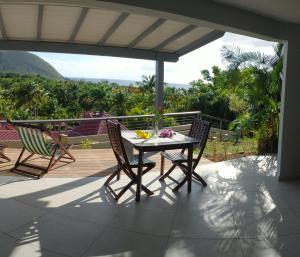 um pátio com uma mesa e cadeiras num deque em Hotel - Résidence Habitation Grande Anse em Deshaies