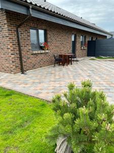 a brick house with a patio with a table and benches at Kuršių Take in Šventoji