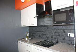 a kitchen with white cabinets and a microwave and a sink at Квартира-студия в ЖК Ботанический сад 10 мкр in Aktau