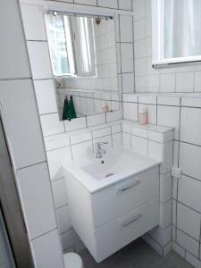 a white bathroom with a sink and a mirror at Appartement confortable à Rosny-sous-Bois, 38m² + Vue sur la ville in Rosny-sous-Bois