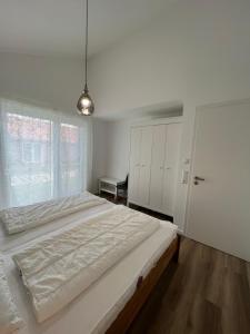 - une chambre blanche avec un grand lit et une fenêtre dans l'établissement Haus JadeMuschel - behagliches Haus mit Aussicht, à Schweiburg