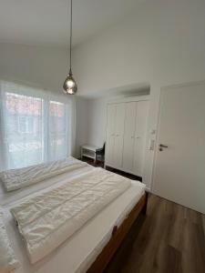 a white bedroom with a large bed and a window at Haus JadeMuschel - behagliches Haus mit Aussicht in Schweiburg