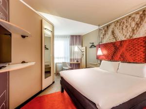 a hotel room with a large bed and a mirror at ibis Frankfurt Centrum in Frankfurt