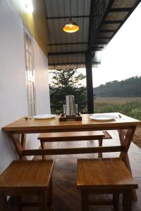 une table en bois et des bancs dans une chambre avec fenêtre dans l'établissement Agronest Farm by LivingStone, à Sultan Bathery