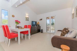 a living room with a couch and a table with red chairs at House Anima in Maslinica
